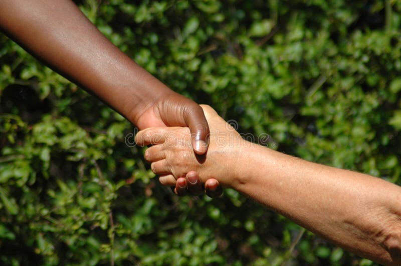 Handshake between a black hand of an African American woman and a white hand of an caucasian woman holding each other to show there agreement. Handshake between a black hand of an African American woman and a white hand of an caucasian woman holding each other to show there agreement