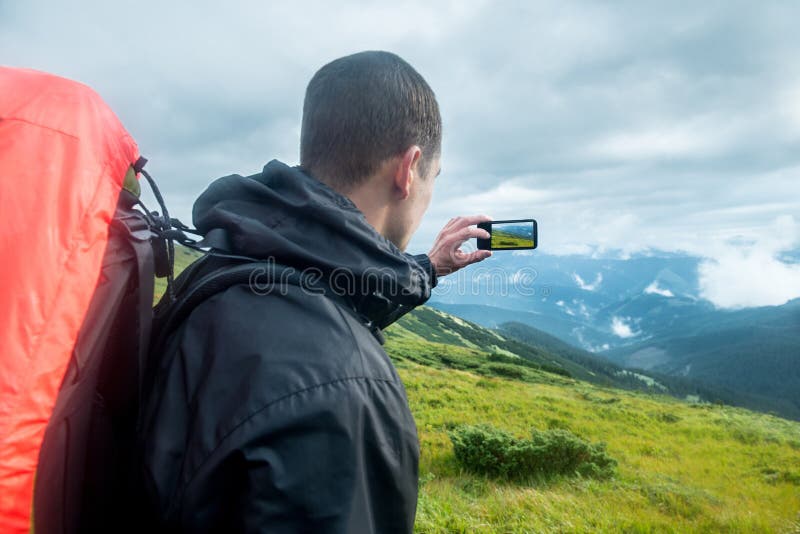 Handelsresande med ryggsäcken och smartphonen på bergen royaltyfri bild Handelsresande med ryggsäcken och smartphonen på bergen royaltyfri bild