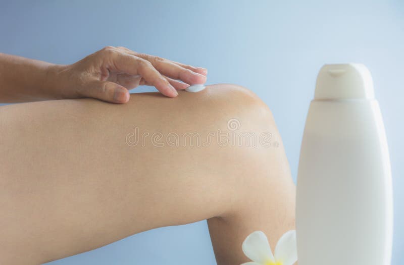 Handen av kvinnan applicerar lotion på hud av knäet med lotionflaskan royaltyfria bilder Handen av kvinnan applicerar lotion på hud av knäet med lotionflaskan royaltyfria bilder
