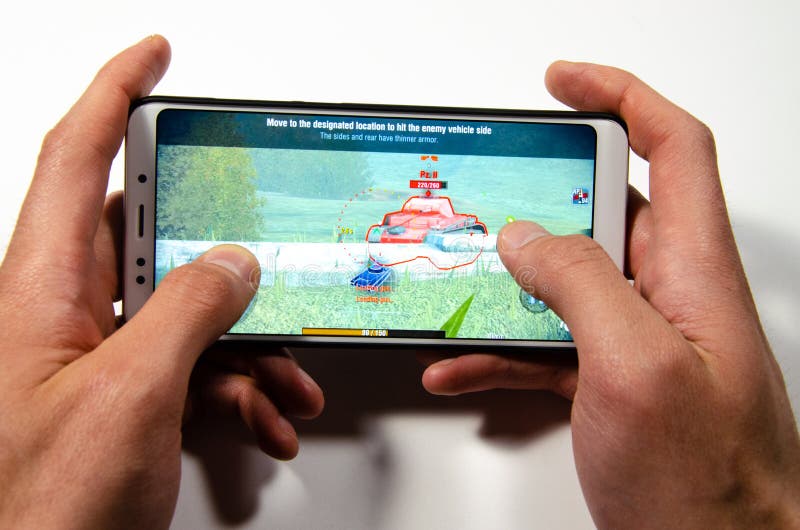 Handen die een smartphone houden waarop het spel, gameplay Gameplay-Wereld van Tanksblitz royalty-vrije stock afbeeldingen Handen die een smartphone houden waarop het spel, gameplay Gameplay-Wereld van Tanksblitz royalty-vrije stock afbeeldingen