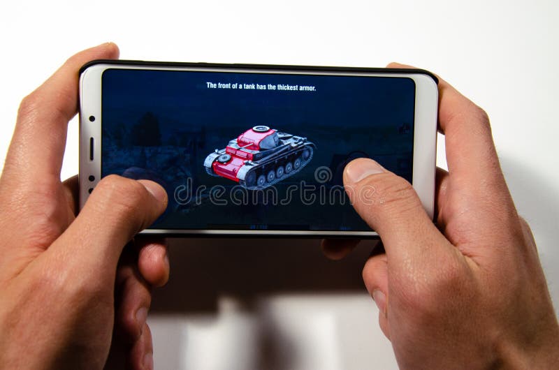 Handen die een smartphone houden waarop het spel, gameplay Gameplay-Wereld van Tanksblitz royalty-vrije stock foto's Handen die een smartphone houden waarop het spel, gameplay Gameplay-Wereld van Tanksblitz royalty-vrije stock foto's