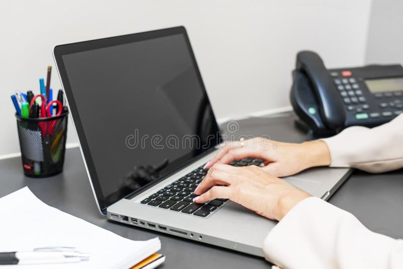 Female hands typing on laptop keyboard at office desk. Female hands typing on laptop keyboard at office desk