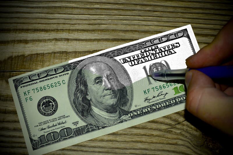 Handen drar räkningen för dollar 100 på en träbakgrund royaltyfri foto Handen drar räkningen för dollar 100 på en träbakgrund royaltyfri foto