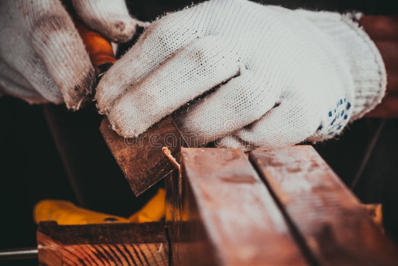 The hand of the asian carpenter taking the chisel to sharpen the wood plank. The hand of the asian carpenter taking the chisel to sharpen the wood plank