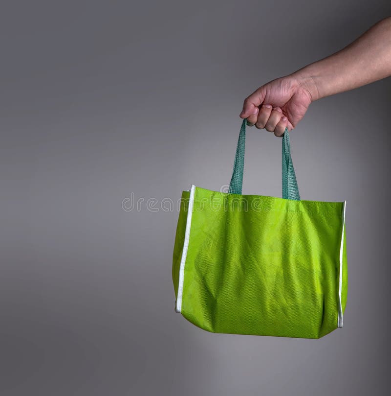 Handen som rymmer en gräsplan, återanvänder den gröna påsen, vänlig shoppingnolla för eco arkivfoton