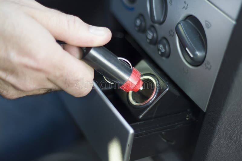 Handen sätter in proppen in i håligheten 12V från cigarettändaren för bil` s arkivfoton Handen sätter in proppen in i håligheten 12V från cigarettändaren för bil` s arkivfoton