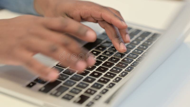 Handen van de afrikaanse man die op het toetsenbord van de laptop typt sluiten