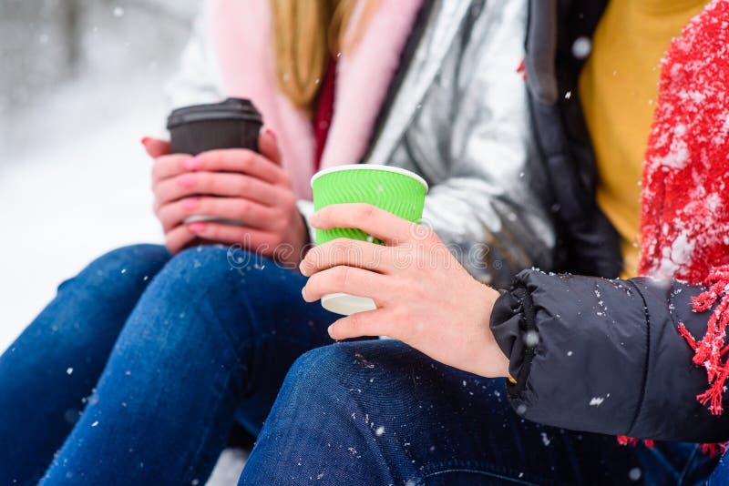 Take away beverages on winter snow background. Hands of couple with cups of hot drinks close-up. Take away beverages on winter snow background. Hands of couple with cups of hot drinks close-up