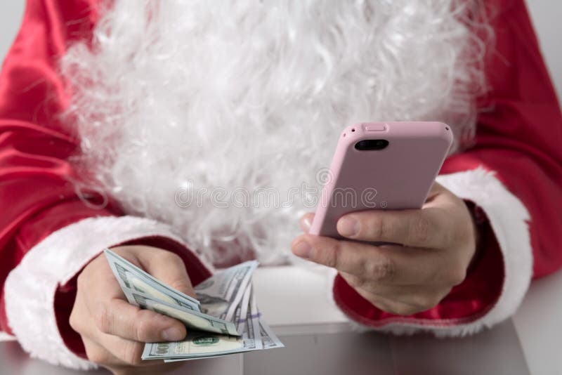 Handen van Santa Claus-holdingsgeld, dollars en smartphone royalty-vrije stock foto's Handen van Santa Claus-holdingsgeld, dollars en smartphone royalty-vrije stock foto's
