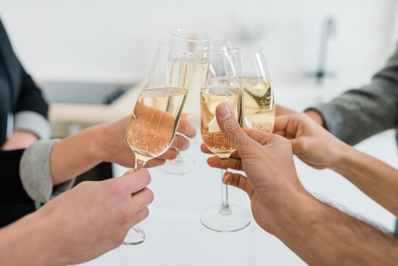 Hands of young friends holding flutes of sparkling of champagne and clinking with them while making toast for holiday at party. Hands of young friends holding flutes of sparkling of champagne and clinking with them while making toast for holiday at party