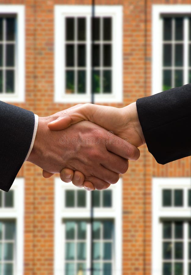 Business hand shake in front of a brick building. Business hand shake in front of a brick building