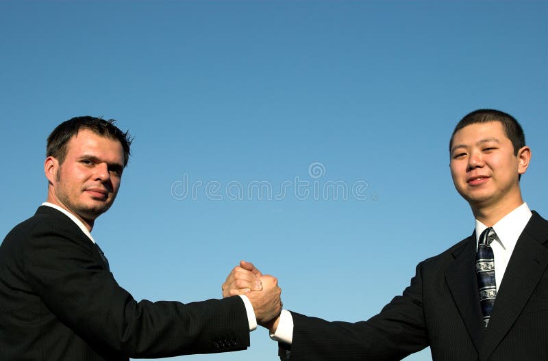 2 businessmen shakking hands with the blue sky behind them. 2 businessmen shakking hands with the blue sky behind them