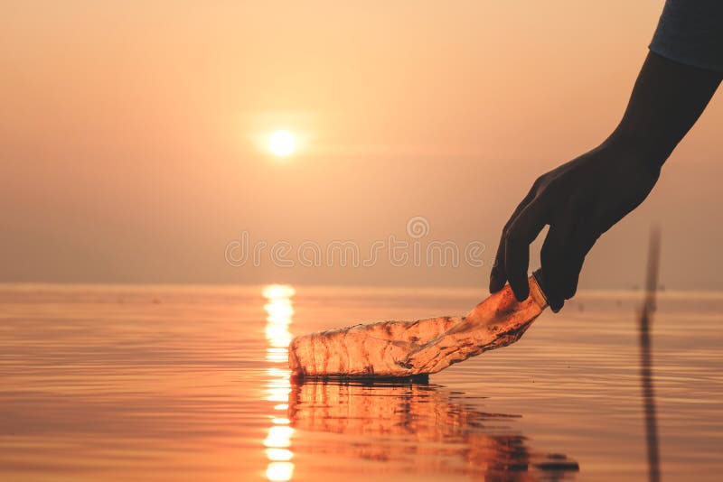 Hand Woman picking up empty of plastic bottle cleaning on the beach , volunteer concept. Environmental pollution. Ecological problem. Hand Woman picking up empty of plastic bottle cleaning on the beach , volunteer concept. Environmental pollution. Ecological problem