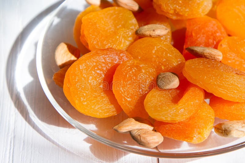 A handful of dried fruit, dried apricots and apricot seeds on a white background