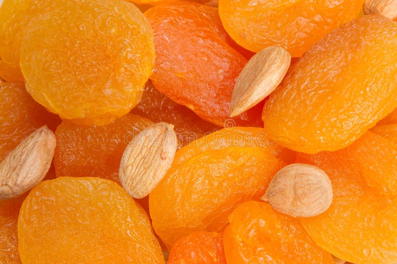 A handful of dried fruit, dried apricots and apricot seeds on a white background