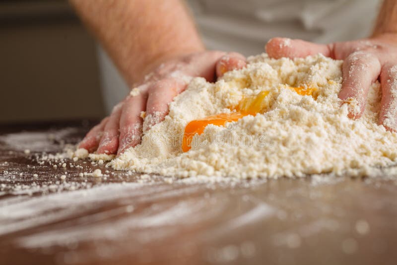 Handful of flour with egg on a rustic kitchen. Against the backg