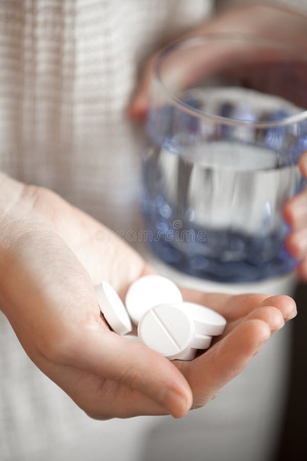 Handful of white round pills and glass of water in womans hands stock images Handful of white round pills and glass of water in womans hands stock images