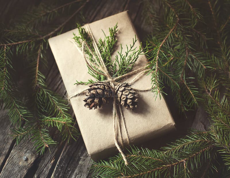 Hand crafted gift on rustic wooden background with with fir branches and cones, toned image. Hand crafted gift on rustic wooden background with with fir branches and cones, toned image