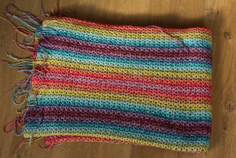 Handgemachte bunte gestrickte Wolldecke auf hölzernem Hintergrund lizenzfreie stockfotos