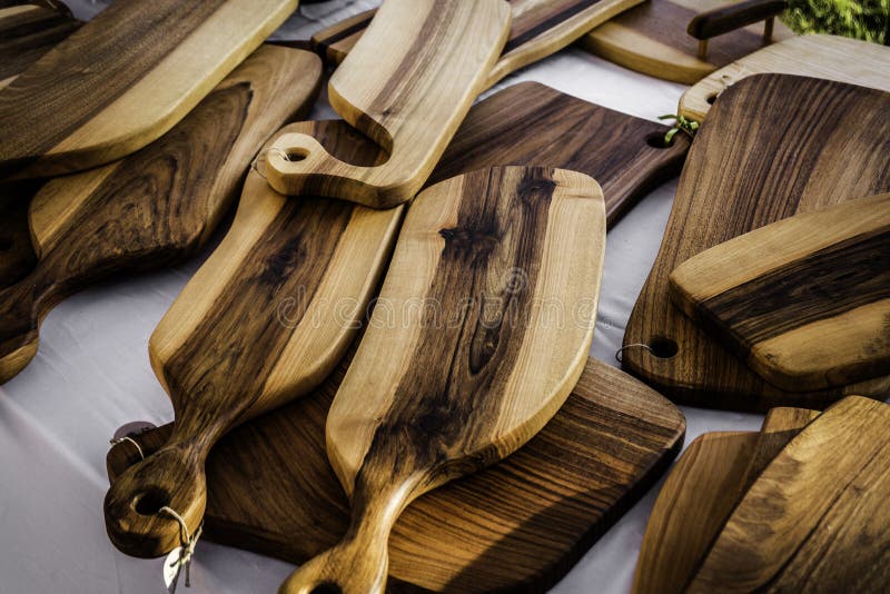 Hand crafted wooden cutting boards stacked for display on a market stall. Hand crafted wooden cutting boards stacked for display on a market stall.