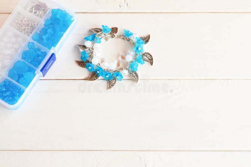Handgemachtes Armband mit Blumen, Perlen und Metallanhängern Organisator mit Zubehör für die Herstellung des Schmucks Hölzerner H stockbild Handgemachtes Armband mit Blumen, Perlen und Metallanhängern Organisator mit Zubehör für die Herstellung des Schmucks Hölzerner H stockbild