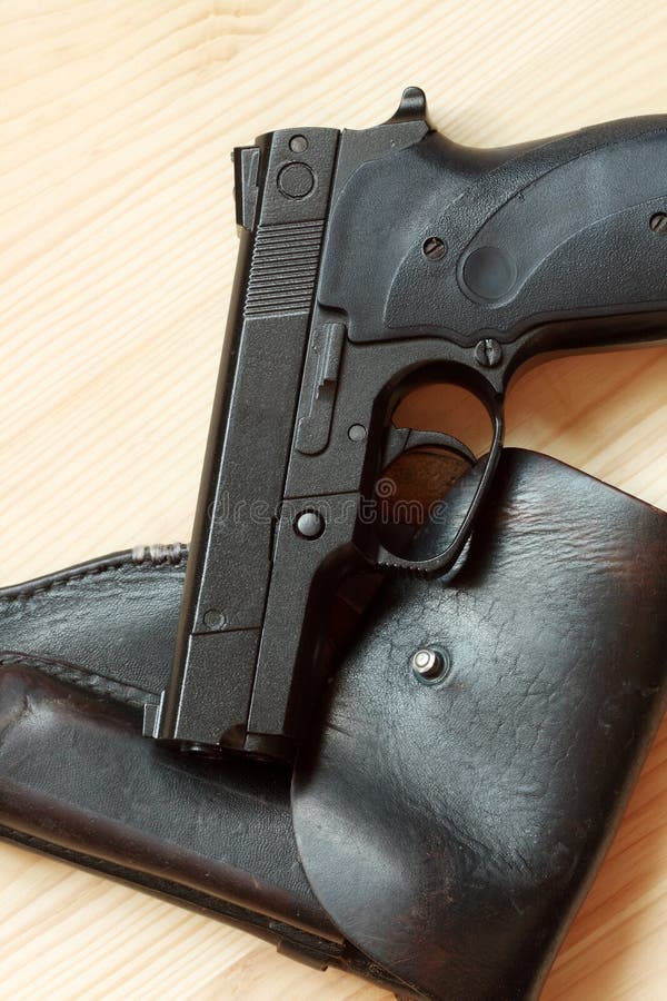 Modern automatic pistol and old leather holster on wooden background. Modern automatic pistol and old leather holster on wooden background