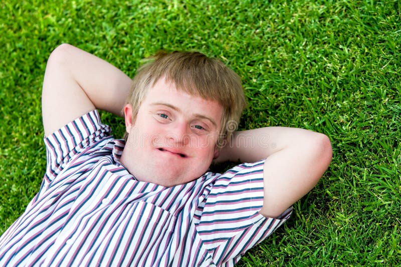 Handicapped boy relaxing on green grass.