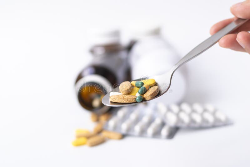 Handinnehavsked med medicinpiller, minnestavlor och kapslar med pillerflaskan på vit bakgrund arkivfoton Handinnehavsked med medicinpiller, minnestavlor och kapslar med pillerflaskan på vit bakgrund arkivfoton