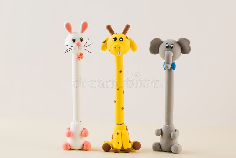 Handles with a body in the form of funny animals made of polymer clay on a beige background. Handles with a body in the form of funny animals made of polymer clay on a beige background