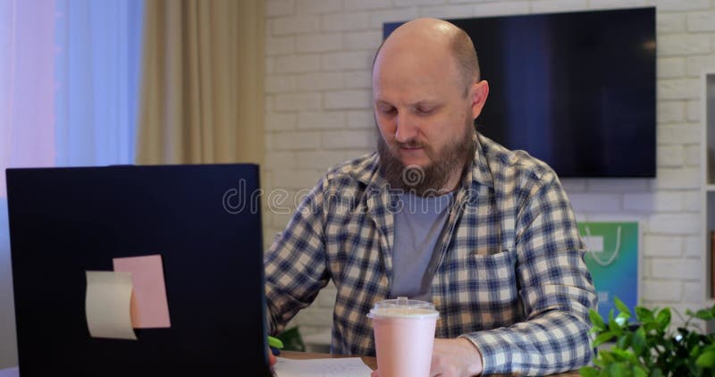 Handlig upptagen man som sitter i rum och arbetar på en bärbar dator. Välskötare maskinskrivning som koncentrerar sig på arbete oc arkivfilmer