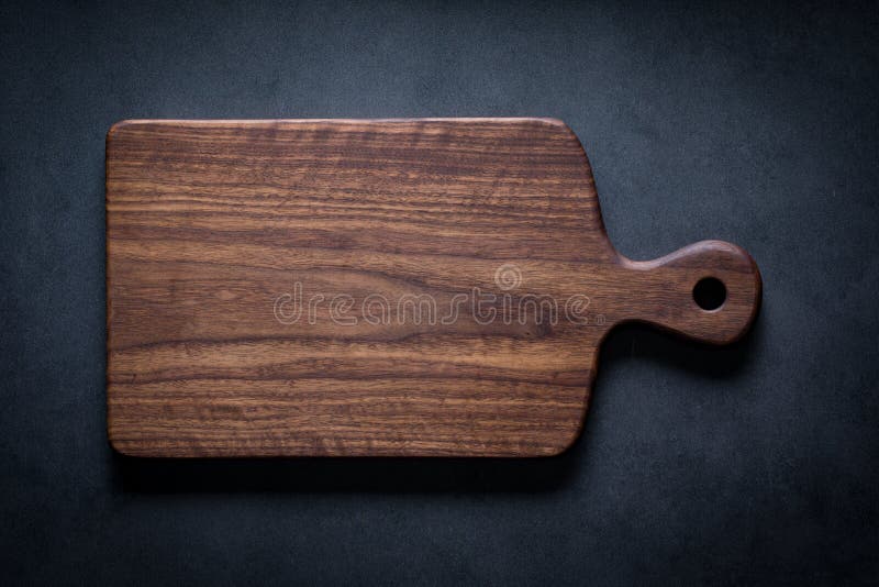 Handmade black walnut wood cutting board on the dark tabletop.