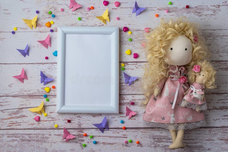 Handmade fabric doll with colorful beads, paper butterflies and white photo frame royalty free stock photos Handmade fabric doll with colorful beads, paper butterflies and white photo frame royalty free stock photos