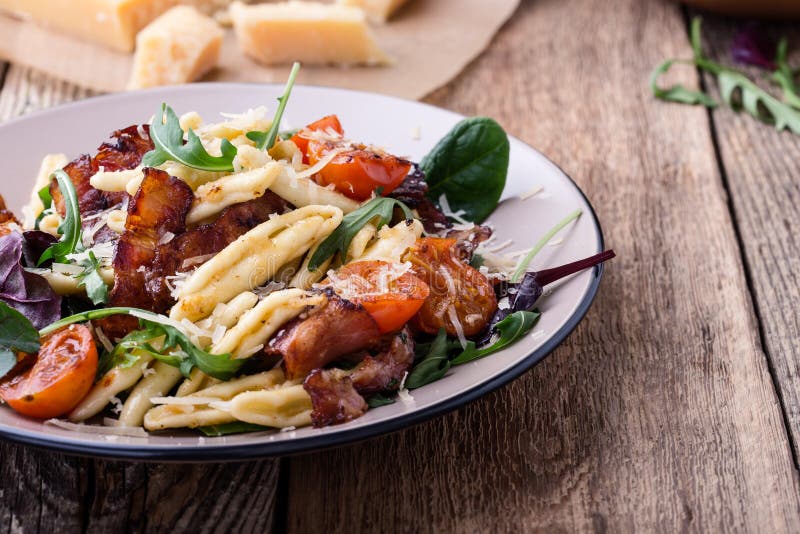 Handmade fusilli pasta with pancetta, roasted cherry tomatoes and fresh green vegetables