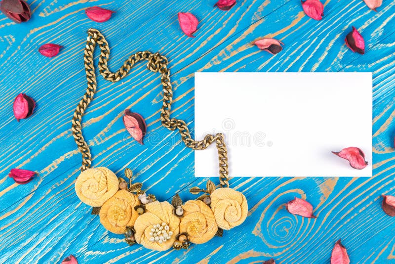 Handmade kolii składać się z pięć kwiatów i kartka z pozdrowieniami z gratulacjami na błękitnym drewnianym tle obraz stock Handmade kolii składać się z pięć kwiatów i kartka z pozdrowieniami z gratulacjami na błękitnym drewnianym tle obraz stock