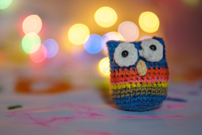 Handmade from wool bound owl on festive background bokeh against lamps