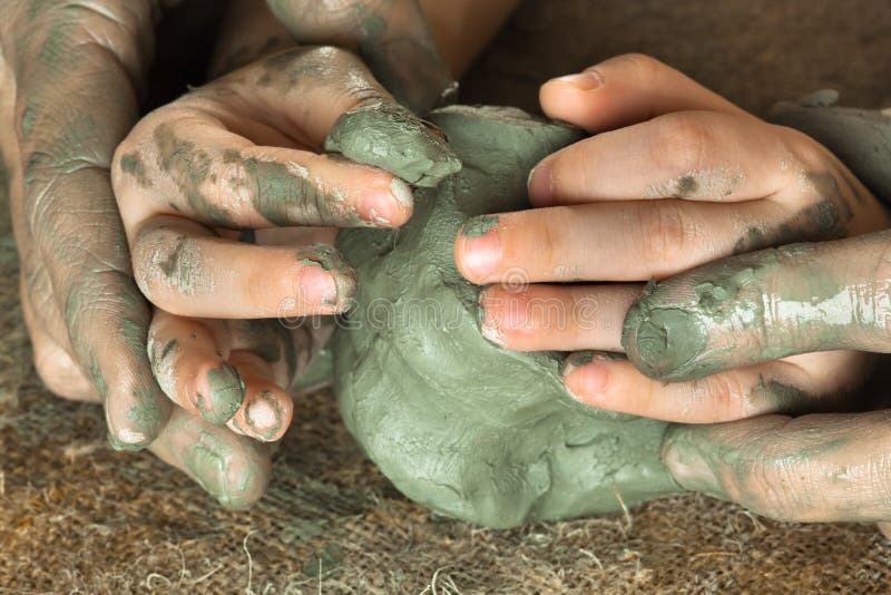 Hands of adult helping child to work with blue clay stock images