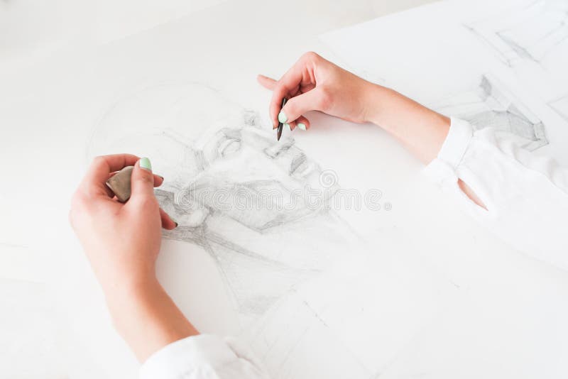 Hands of artist drawing portrait with pencil