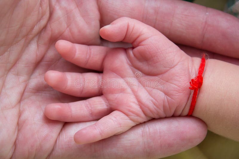 Hands of the Baby and the Father,hand Baby with a Red Thread in the