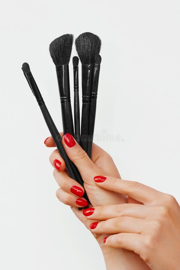 Hands of a Beautiful Woman with Red Nails and Makeup Brushes - isolated on white royalty free stock photo Hands of a Beautiful Woman with Red Nails and Makeup Brushes - isolated on white royalty free stock photo