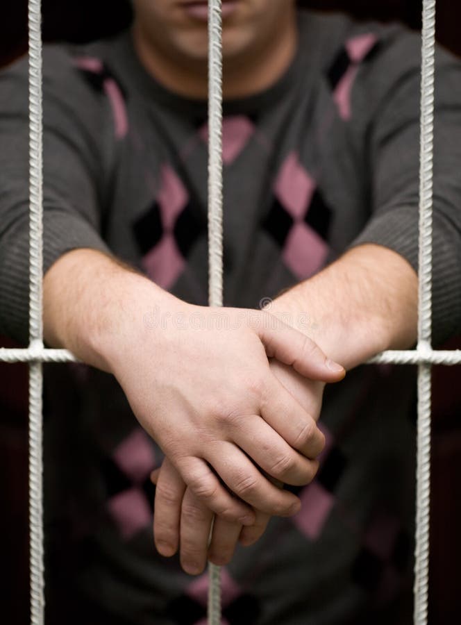 Hands behind bars stock photo