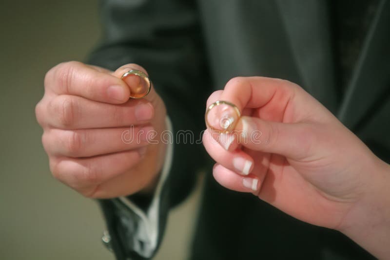 he hands of the bride and groom with rings in hands in the church