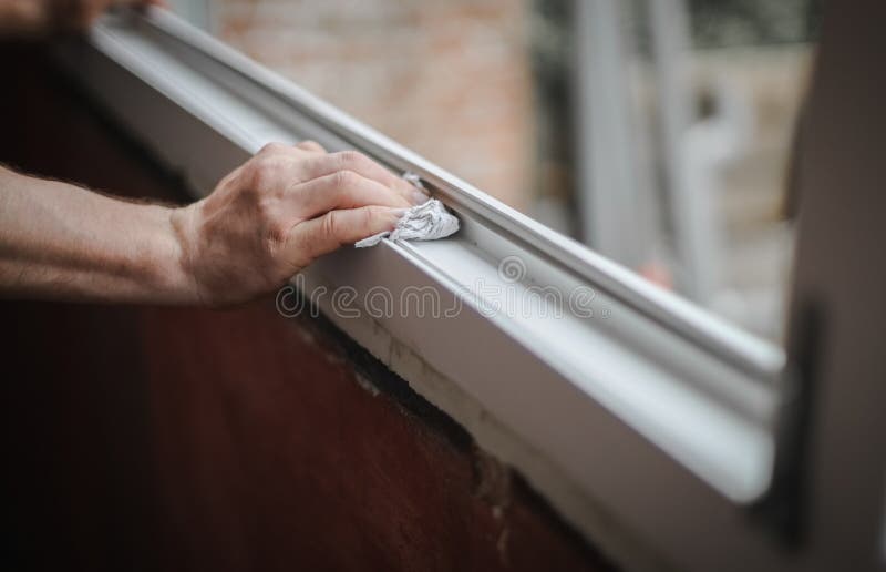 Hands of a Caucasian young man cleans his hands with a dry paper napkin the interior opening of the window frame, close-up side view with selective focus. The concept of home renovation, washing window frames. Hands of a Caucasian young man cleans his hands with a dry paper napkin the interior opening of the window frame, close-up side view with selective focus. The concept of home renovation, washing window frames.