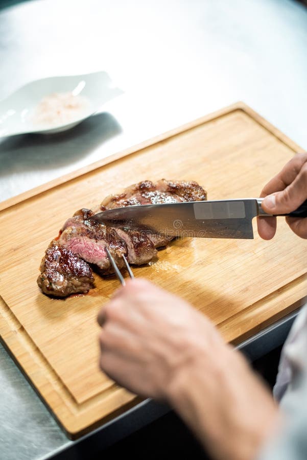 Hands of Chef with Sharp Knife Cutting Roasted Beef Steak on Wooden Board Stock Image Image of