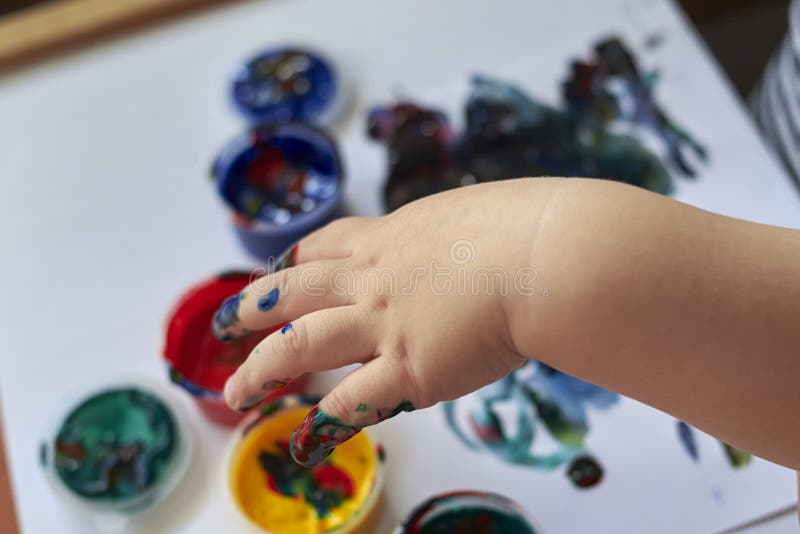 Hands of a child who paints with bright finger paints, the early development of the child