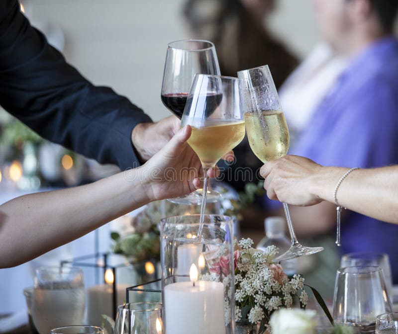 Hands Clinking Three Wine Glasses Together in a Toast at a Dinner Party