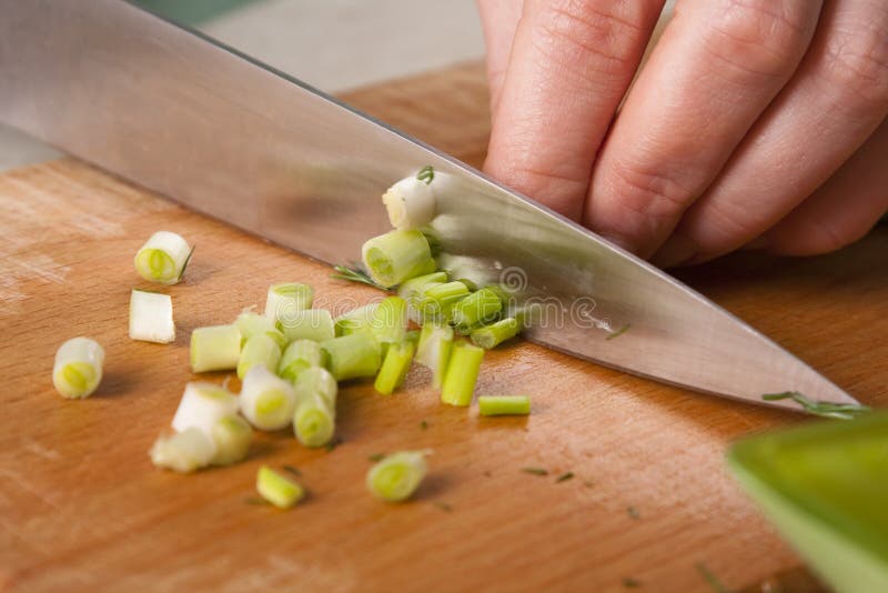 Hands of cook cutting spring onions