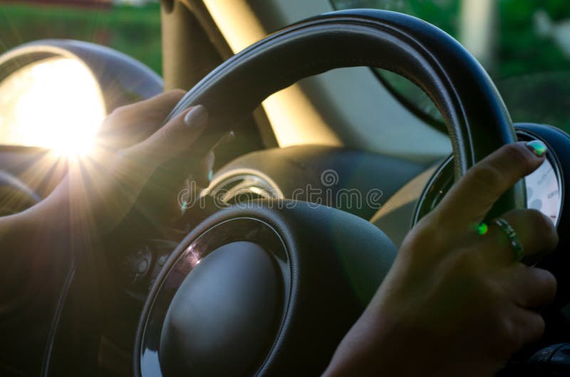 Hands of the Driver on the Steering Wheel while Driving Stock Photo