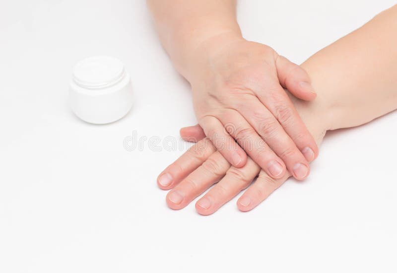 The hands of an elderly woman on a white background and a complex cream with vitamin against wrinkles and tightness on royalty free stock photo The hands of an elderly woman on a white background and a complex cream with vitamin against wrinkles and tightness on royalty free stock photo