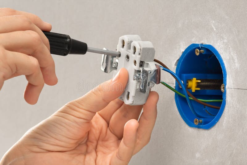 Hands of Electrician with Screwdriver Installing Light Switch Stock