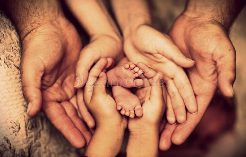 Hands of father, mother, daughter keep little feet baby. Friendly happy family